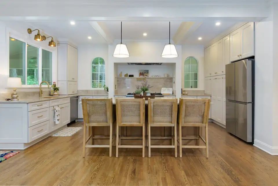 Kitchen remodeling Marietta team's white kitchen remodel with a large island, woven counter stools, two white pendants and arched windows