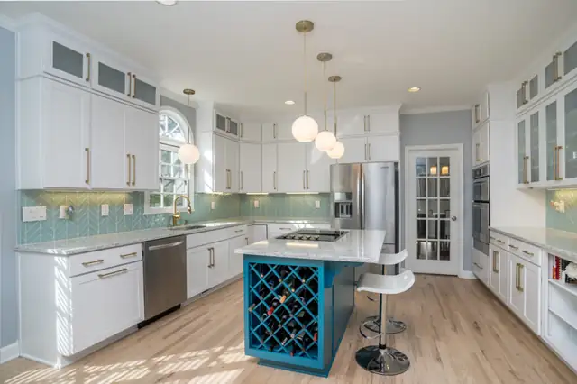 White kitchen with glass-front upper cabinets, a teal island with built-in wine storage, globe pendants and a teal tile backsplash