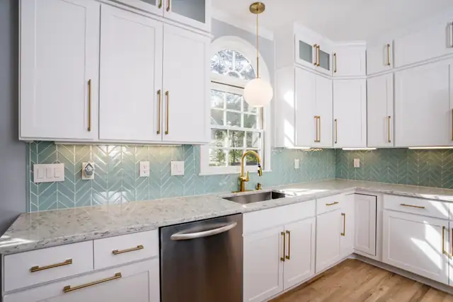 Refaced white kitchen with a teal tile backsplash, brass pendant lights and white shaker doors with gold pulls